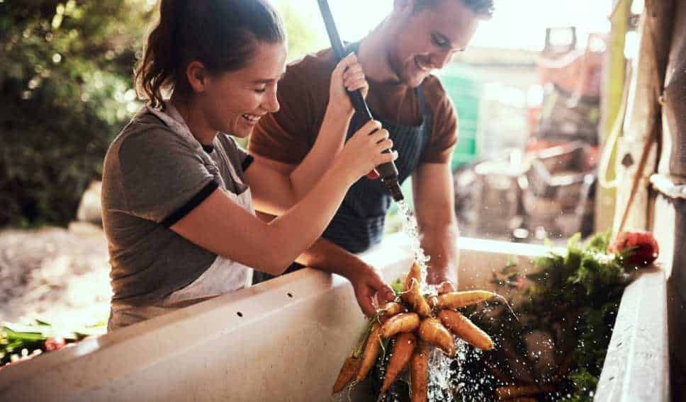 a couple is washing the carrots